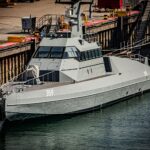 A grey military ship docked in Cherbourg-en-Cotentin, Normandy, reflecting modern naval architecture.