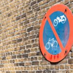Traffic sign prohibiting cycling against a brick wall brightly lit by sunlight.