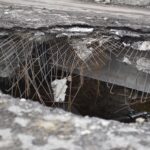 A close-up of a damaged concrete structure with exposed rebar, depicting urban decay.