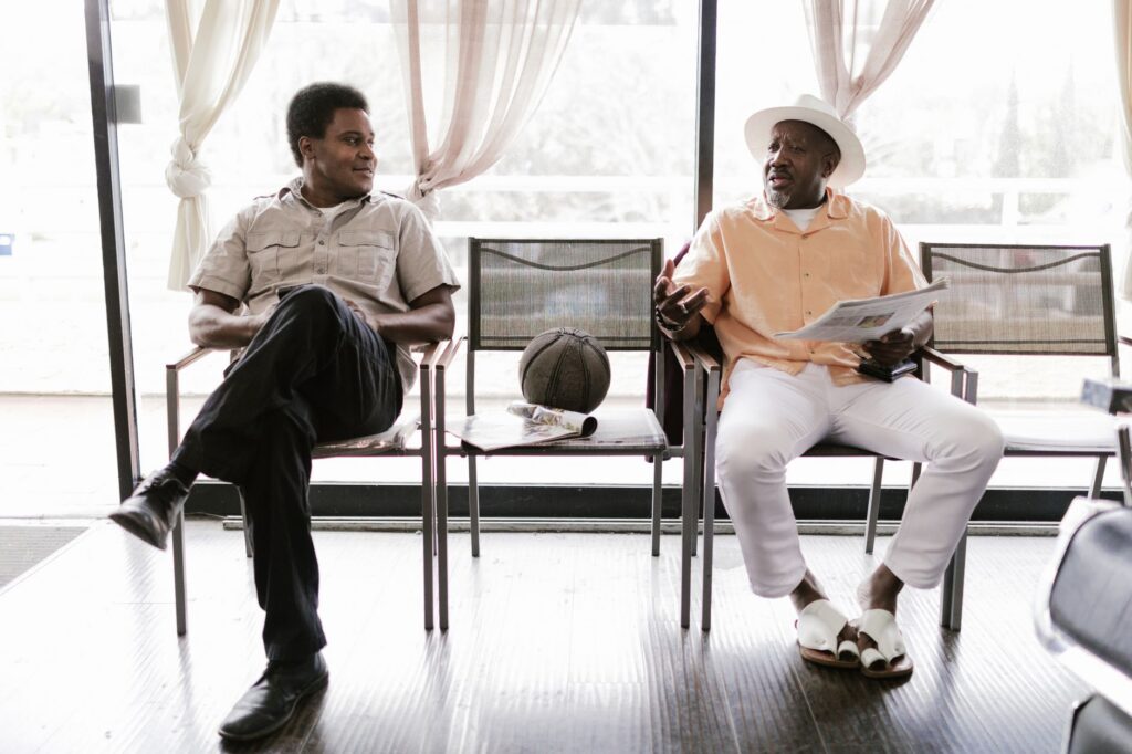 Two adults chatting in a bright barbershop while waiting, showcasing casual interaction.