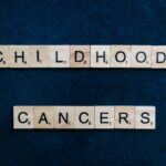 Scrabble tiles arranged to spell 'Childhood Cancers' on a dark blue background.