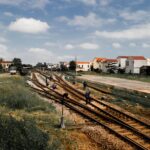 Workers maintaining railroads in a rural town under blue skies.