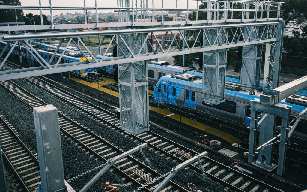 Aerial view of modern railways and blue train in urban setting, showcasing transportation infrastructure.