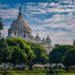 View of the iconic Victoria Memorial in Kolkata surrounded by lush greenery on a sunny day.