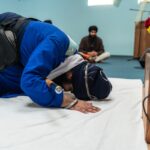 A Sikh man prostrating in prayer inside a gurdwara, emphasizing devotion and spirituality.