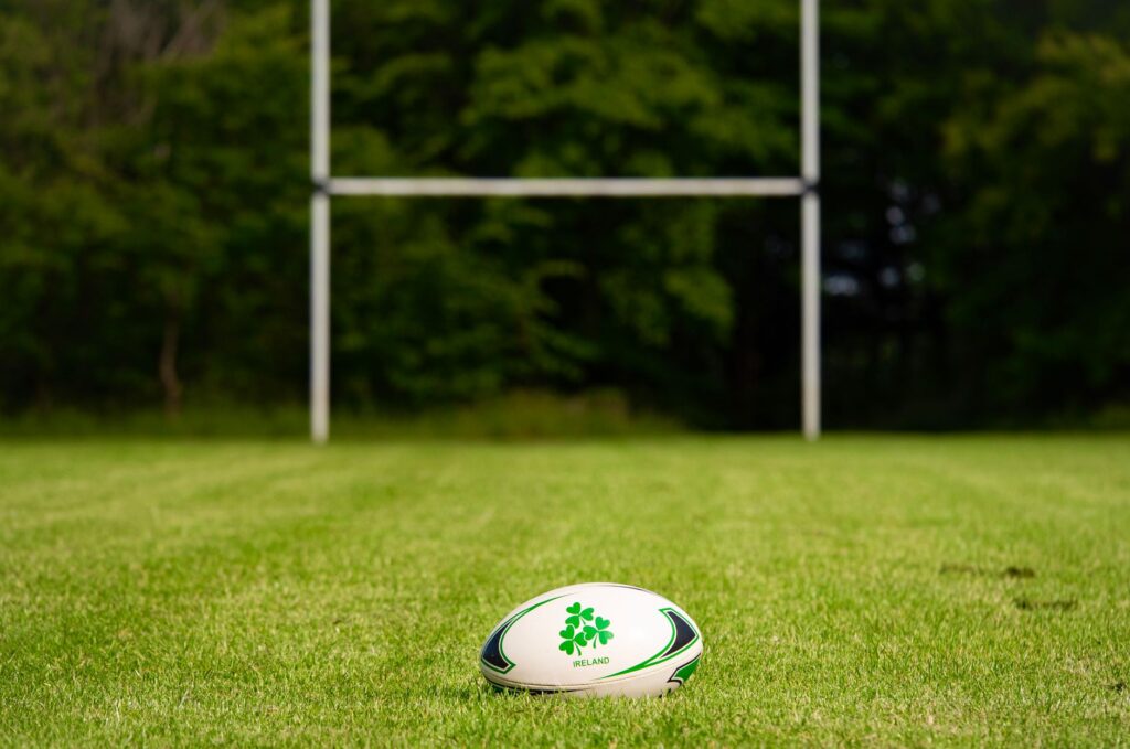Rugby ball on a grassy field with goal posts in the background, Galway, Ireland.