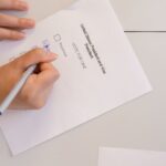 Hand placing vote on ballot form during election process, highlighting civic duty and democracy.