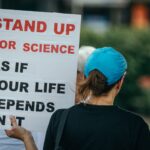 Back view of person holding a protest sign advocating for science in a public setting.