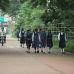 Group of schoolgirls walking along a tree-lined street in Raipur, India.