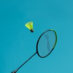 A thrilling action shot of a badminton racket hitting a shuttlecock against a clear blue sky.