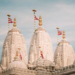 Beautiful white stone spires of BAPS Shri Swaminarayan temple against a clear sky.