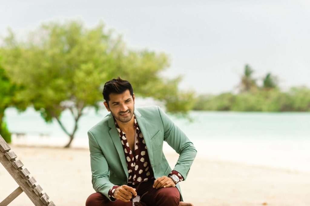 Fashionable man posing at a scenic Maldives beach resort in designer wear.