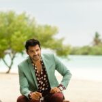 Fashionable man posing at a scenic Maldives beach resort in designer wear.