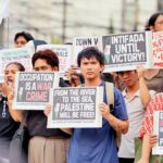 A group of demonstrators holding signs in support of Palestine at a protest rally.