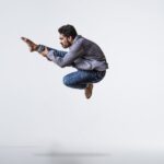 A male contemporary dancer gracefully leaps with precision and energy in a studio setting.