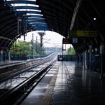A quiet afternoon at a New Delhi metro station with wet tracks post rain, reflecting urban life.