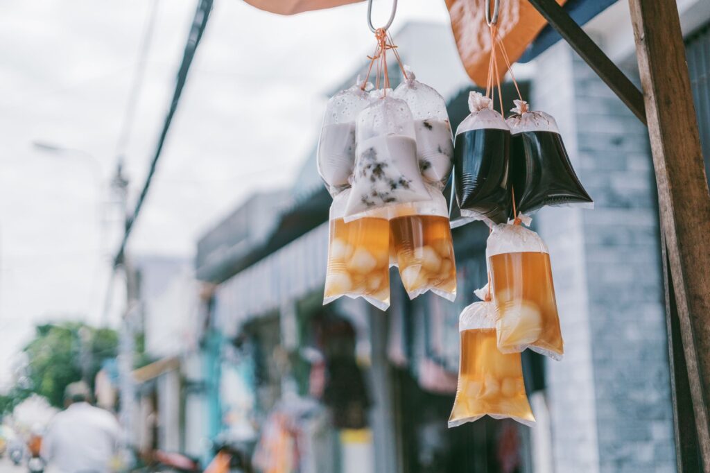 Plastic bags of drinks hanging in an urban street setting showcasing local street food culture.