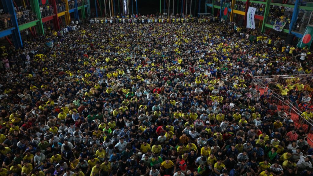 A vibrant gathering of diverse people at an indoor event in Dhaka, Bangladesh.