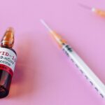 Close-up of a COVID-19 vaccine vial and syringes against a pink background, symbolizing healthcare.