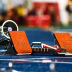 Close-up of athletics starting blocks on a wet blue track, ready for a race.