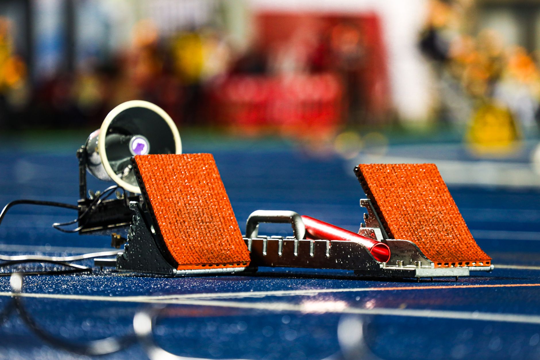 Close-up of athletics starting blocks on a wet blue track, ready for a race.