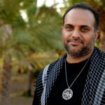 A serene portrait of a man wearing traditional attire in a palm grove in Karbala, Iraq.