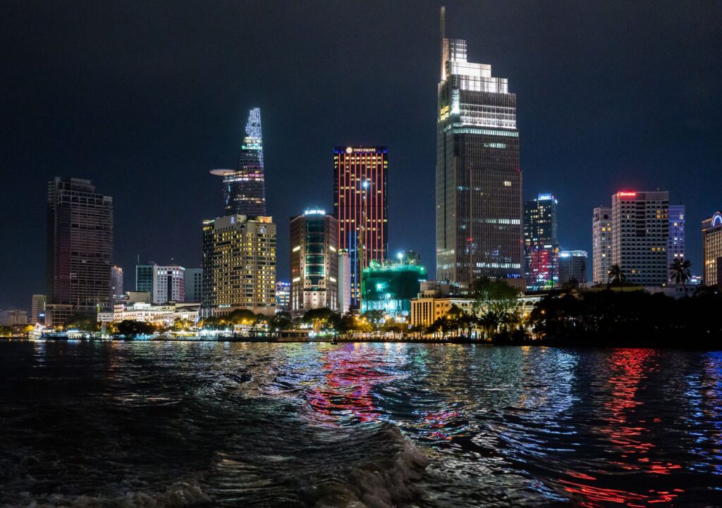 Beautiful night view of Ho Chi Minh City skyline with illuminated skyscrapers reflecting on the water.