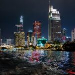 Beautiful night view of Ho Chi Minh City skyline with illuminated skyscrapers reflecting on the water.