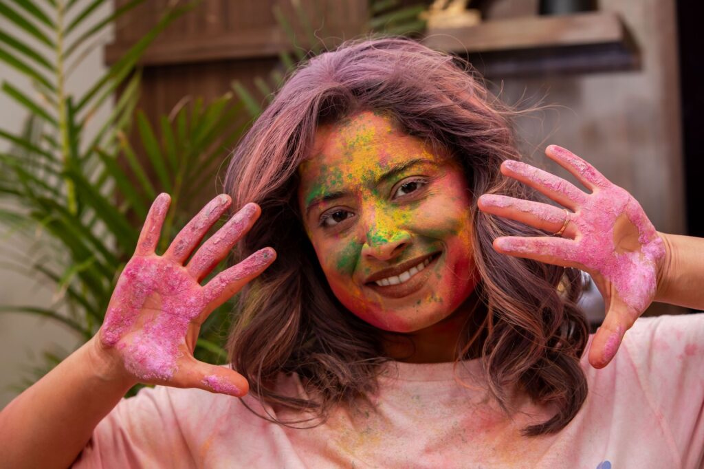 Cheerful woman with vibrant holi powder on face, enjoying the festival.