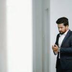 Elegant South Asian man in a suit adjusting his sleeves indoors.