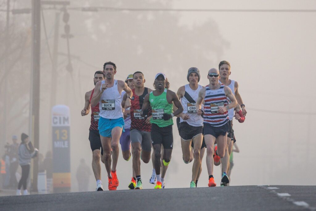 Dynamic shot of marathon runners competing in a misty urban setting, emphasizing endurance and athleticism.
