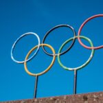 The iconic Olympic rings stand against a vibrant blue sky, symbolizing global unity and sportsmanship.