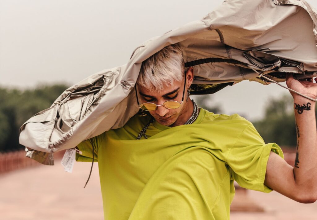 Trendy male model with modern fashion look posing outdoors in vibrant outfit.