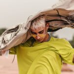 Trendy male model with modern fashion look posing outdoors in vibrant outfit.