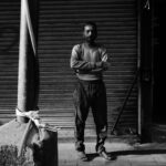 Black and white portrait of a man standing on a street in Delhi, India, conveys a moody urban atmosphere.