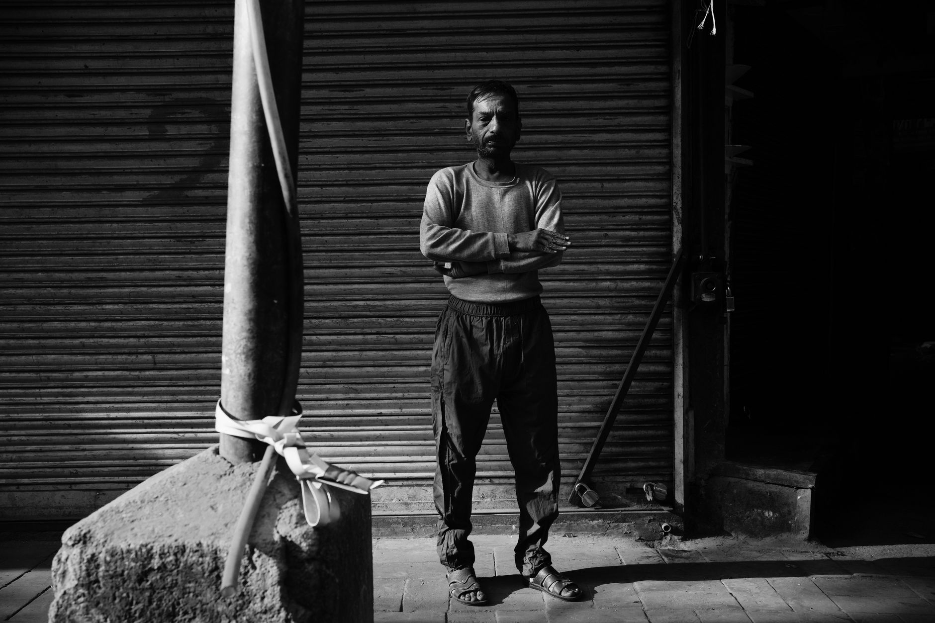 Black and white portrait of a man standing on a street in Delhi, India, conveys a moody urban atmosphere.
