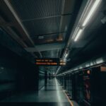A dimly lit urban subway platform in New Delhi with signs in multiple languages.