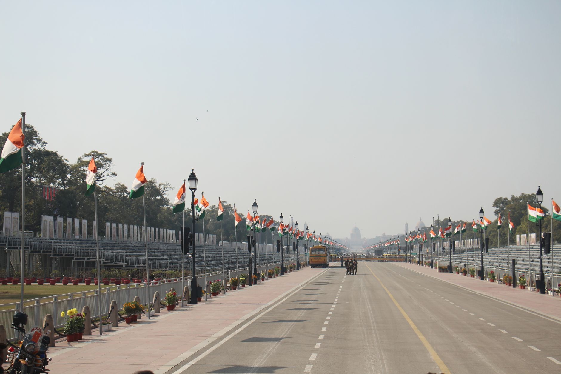 Indian flags line Rajpath, Delhi, during Republic Day preparations. Clear sky, wide view.