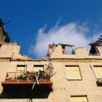A destroyed residential building in Kharkiv, Ukraine under a blue sky.