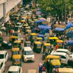 Dynamic aerial view of a busy New Delhi street with auto-rickshaws and pedestrians in a lively market.