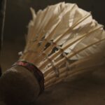 Detailed view of a feathered shuttlecock used in badminton, lying on the ground.