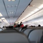 Passengers and flight attendant inside a Vietnam commercial aircraft. Travel safety with masks.