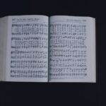 From above of pages of opened book with music notes placed on black background