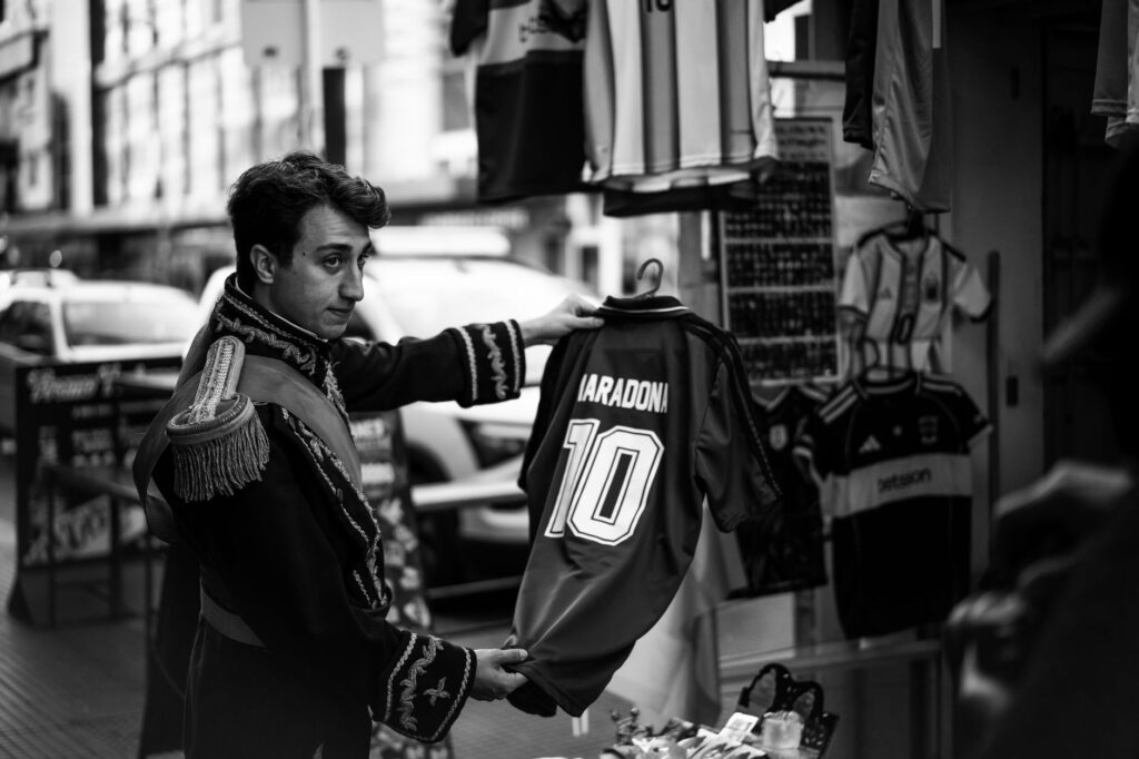 Street vendor holds a Maradona jersey in Buenos Aires. Black and white photograph with a vintage vibe.