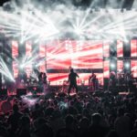 Energetic live music concert featuring performers on a vibrant stage, captivating a large audience.