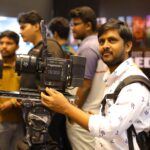 Photographer handling camera equipment at a film expo in Hyderabad.