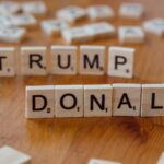 Close-up of Scrabble tiles spelling 'Donald Trump' on a wooden table.