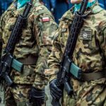 Polish soldiers in uniform standing in formation with rifles, showcasing military discipline.