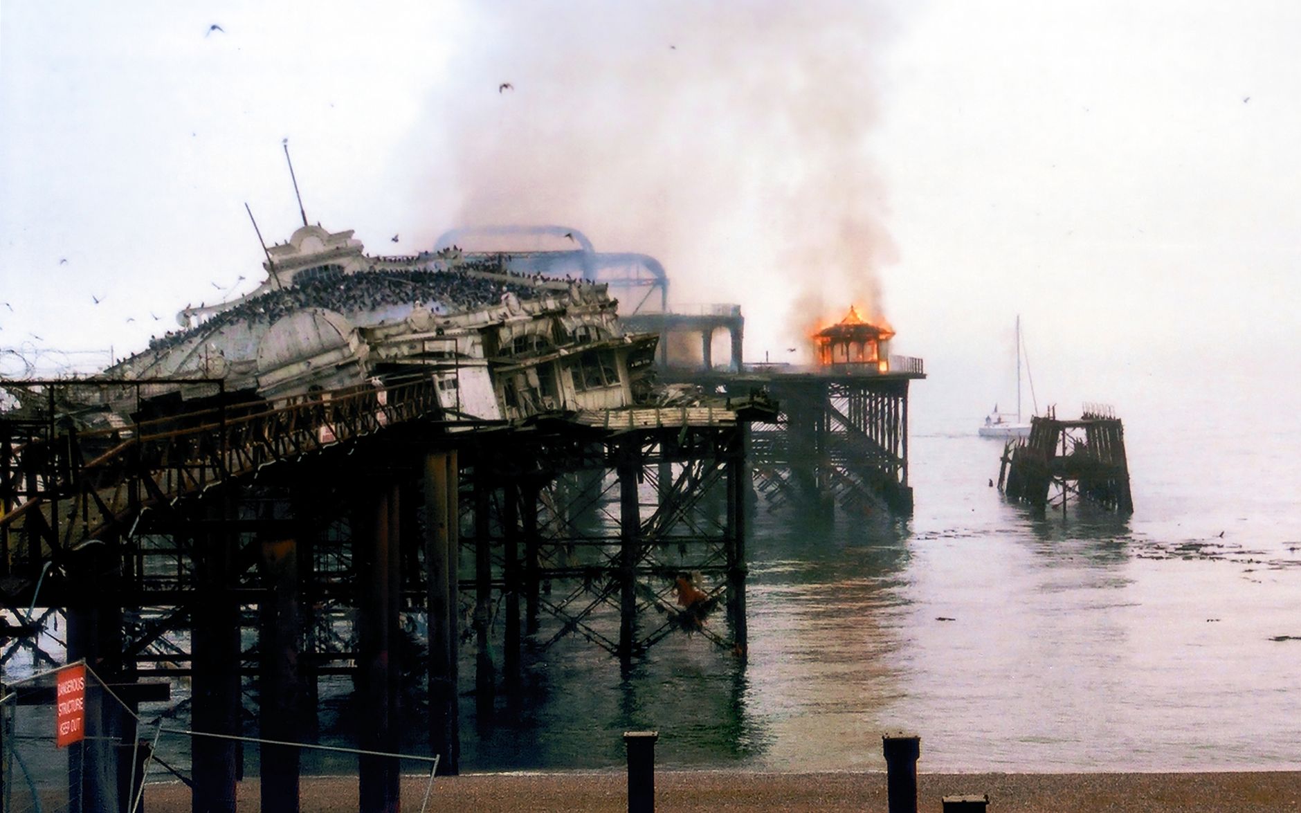 Smoke and fire engulf the historic West Pier in Brighton, showcasing disaster and decay.