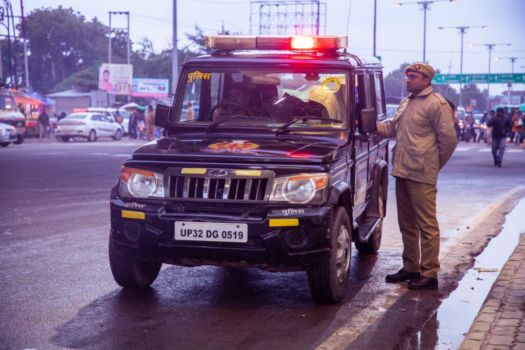 An Indian police officer stands beside a police SUV on a busy roadside in Uttar Pradesh.